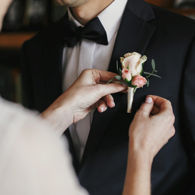 Beautiful,Bride,Putting,On,Stylish,Simple,Boutonniere,With,Roses,On